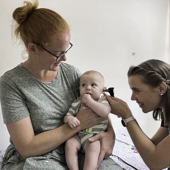 Dr. Rockhill examining a baby with mother